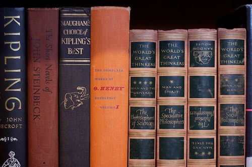 A close row of worn hardcover books on a thrift-store shelf.