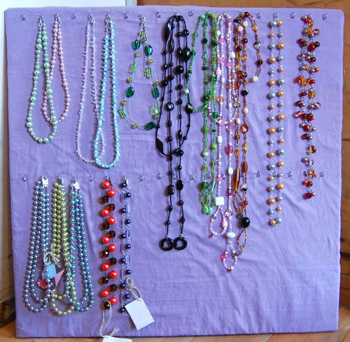Rows of colourful beaded necklaces pinned to a board — handmade goods ready to list.
